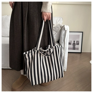 Detail of a large black and white striped canvas tote bag in a cozy home lifestyle setting