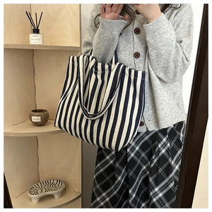 Detail of a large black and white striped canvas tote bag in a cozy lifestyle setting