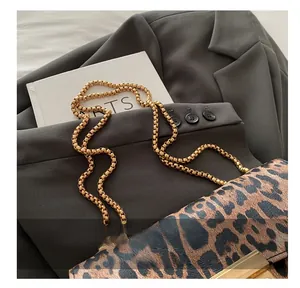 Detailansicht der Umhängetasche mit Leopardenmuster und goldener Kette auf Kunstbuch