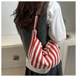Detail of red and white striped canvas crossbody bag featuring a curved dumpling shape