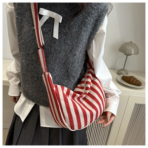 Close-up of red and white striped canvas dumpling bag worn by model with wide strap