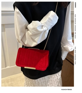 Detail of red velvet flap bag featuring vertical stripe texture and gold metal edge trim