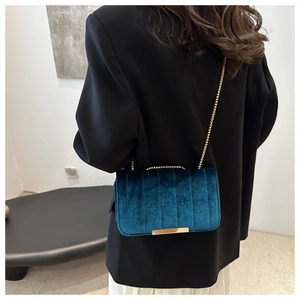 Detail view of peacock blue velvet crossbody bag with gold chain and vertical quilting