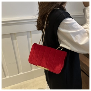 Detail of red velvet crossbody bag with vertical quilting and gold bead chain strap