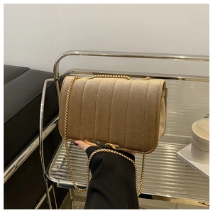 Detail of champagne gold velvet crossbody bag featuring vertical quilted pleats and chain