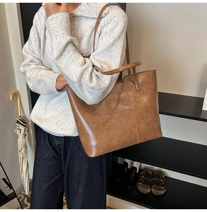 Brown faux leather tote bag worn by model showing large capacity and matte texture