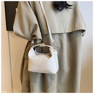 Detailed close-up of white woven texture and gold hardware on a stylish crossbody bag