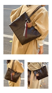 Detail view of large brown oil wax leather tote bag with plush bear charm accessory