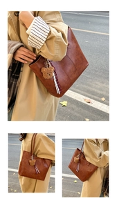 Detail of brown faux leather tote bag with plush bear charm and ribbon on beige coat