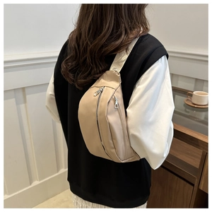Rear view of a model wearing a beige nylon crossbody chest bag with silver zippers
