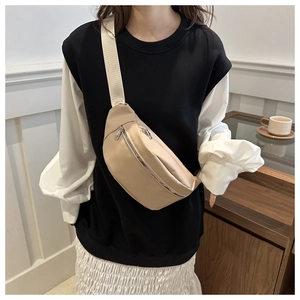 Detail of minimalist beige canvas crossbody bag with dual zipper pockets on a model