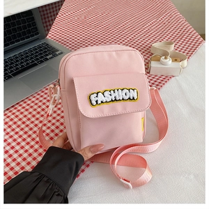 Detail of pink canvas crossbody bag with Fashion patch and adjustable shoulder strap