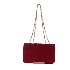 Red velvet crossbody bag with elegant gold chain strap and metal trim on white background
