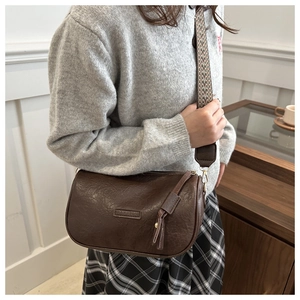 Detail of vintage brown pillow bag with patterned wide strap and gold hardware accents