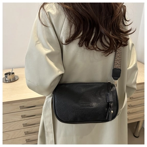 Detail of vintage black pillow bag with stylish wide geometric patterned shoulder strap