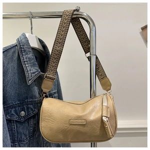 Detail der beigen PU-Leder Schultertasche mit breitem Webriemen und geprägter Textur
