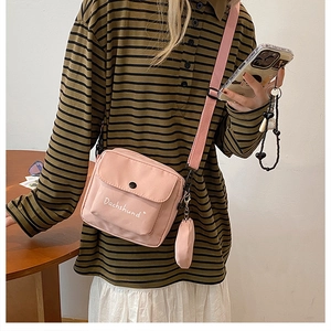 Pink canvas crossbody bag featuring adjustable strap and matching round coin purse detail