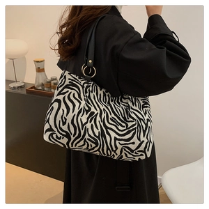 Detailansicht der Zebra-Canvas-Tasche mit schwarzem Riemen und goldenen Metallringen