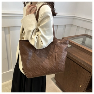 Detail of dark brown woven leather tote bag texture and long shoulder strap