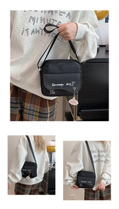 Detail of black nylon crossbody bag featuring a sausage dog graphic and pink bear charm