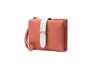 Detail of coral pink leather wallet featuring a floral pattern band and gold bow charm