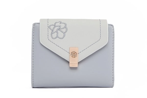 Close-up of floral embroidery and branded rose gold metal buckle on a faux leather wallet
