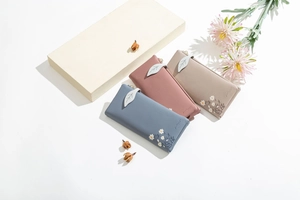 Detailed view of PU leather wallets with daisy print and leaf-shaped zipper charms