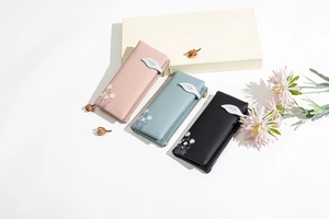 Close-up of floral print wallets with white leaf buckle and side metal zipper details