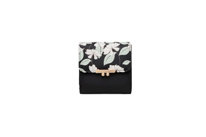 Close-up of trifold floral print wallet with golden logo plate and textured black leather