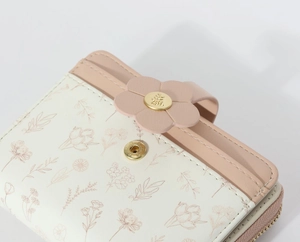 Detail of pink petal clasp with golden metal ornament on printed faux leather wallet