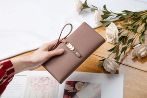 Close-up of a dusty rose long PU leather wallet with gold hardware and wrist strap