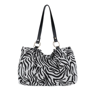 Schicke Canvas-Schultertasche mit Zebramuster, Ledergriffen und goldenen Metallringen