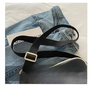 Detail eines verstellbaren schwarzen Stoffschultergurts und weißen Verzierungen an der Tasche