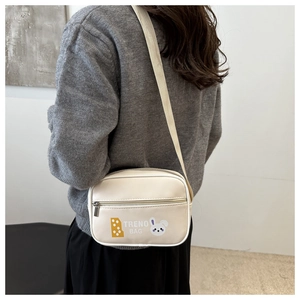 Detailansicht einer beigen Stepptasche mit Hasen-Print und gewebtem Gurt von hinten gesehen