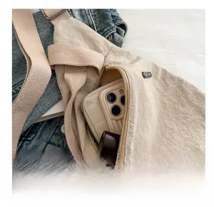 Detail shot showing internal capacity of the beige nylon crossbody bag with zipper
