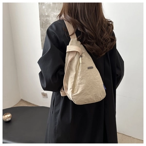 Detailed back view of a beige minimalist nylon crossbody bag worn across the body