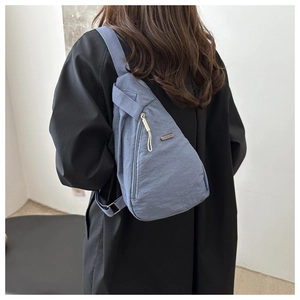 Close-up of fog blue nylon crossbody bag featuring waterproof texture and metal brand tag