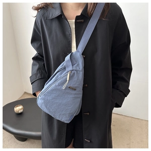 Detailaufnahme der dunkelblauen Nylon-Umhängetasche mit Metall-Logo und Trageriemen