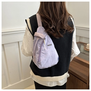 Back view of model wearing a lavender pleated nylon crossbody chest bag with wide strap