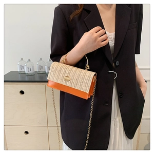 Détail du sac en paille tressée avec cuir orange, poignée métallique et bandoulière chaîne