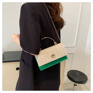 Détail du sac en paille tressée et cuir vert avec poignée en métal doré et bandoulière chaîne