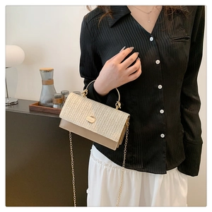 Détail du sac bandoulière en paille tressée et cuir avec chaîne et poignée dorée