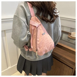Rear view of a pink nylon crossbody chest bag worn over a minimalist casual outfit