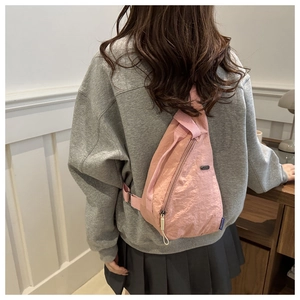 Detailed back view of pink lightweight nylon chest bag on model with blue label