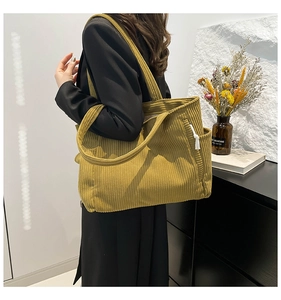Detail of yellow corduroy tote bag featuring side pockets and adjustable drawstring