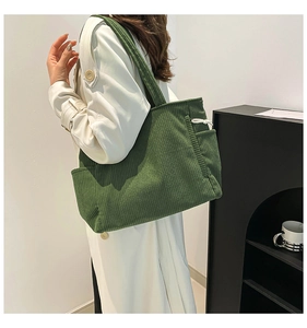 Detail of green corduroy tote bag showing striped texture and drawstring side pocket