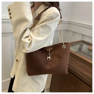 Detail view of dark brown frosted tote bag featuring gold chain strap and deer charm