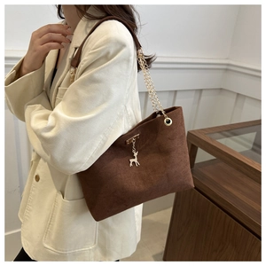 Brown suede tote bag with gold deer pendant and chain strap on a model shoulder