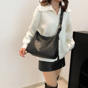 Minimalist black leather hobo tote bag with adjustable shoulder strap on model