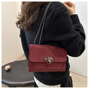 Détail du sac bandoulière en daim rouge foncé avec fermoir argenté et bandoulière chaîne